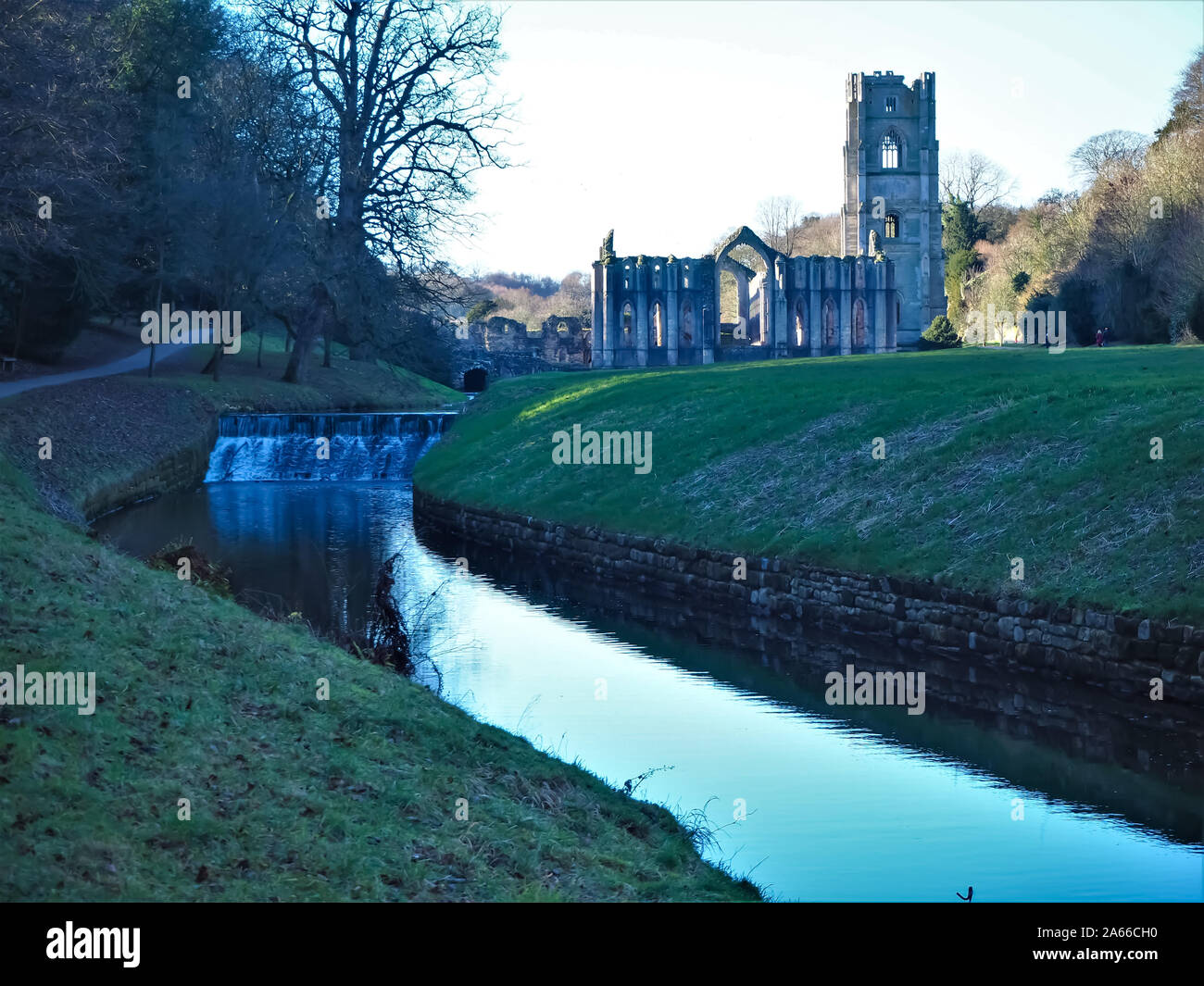 Anzeigen von Fountains Abbey, North Yorkshire, England, aus einem Pfad am Fluss Skell in die studley Royal Water Gardens an einem frostigen Morgen Stockfoto