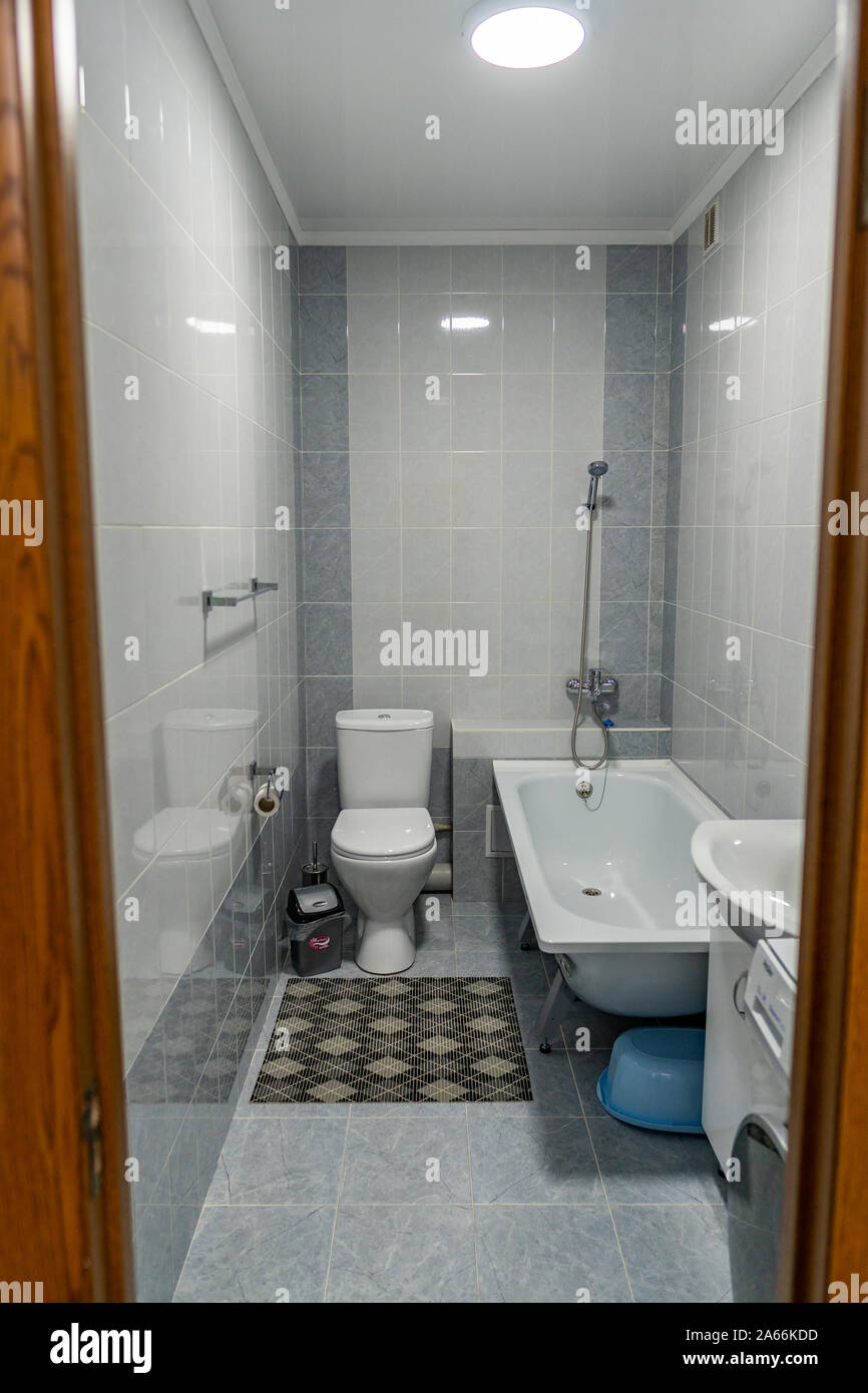 Apartment einfaches Bad mit WC Badewanne Fußmatte für die Füße und Toilette Stockfoto
