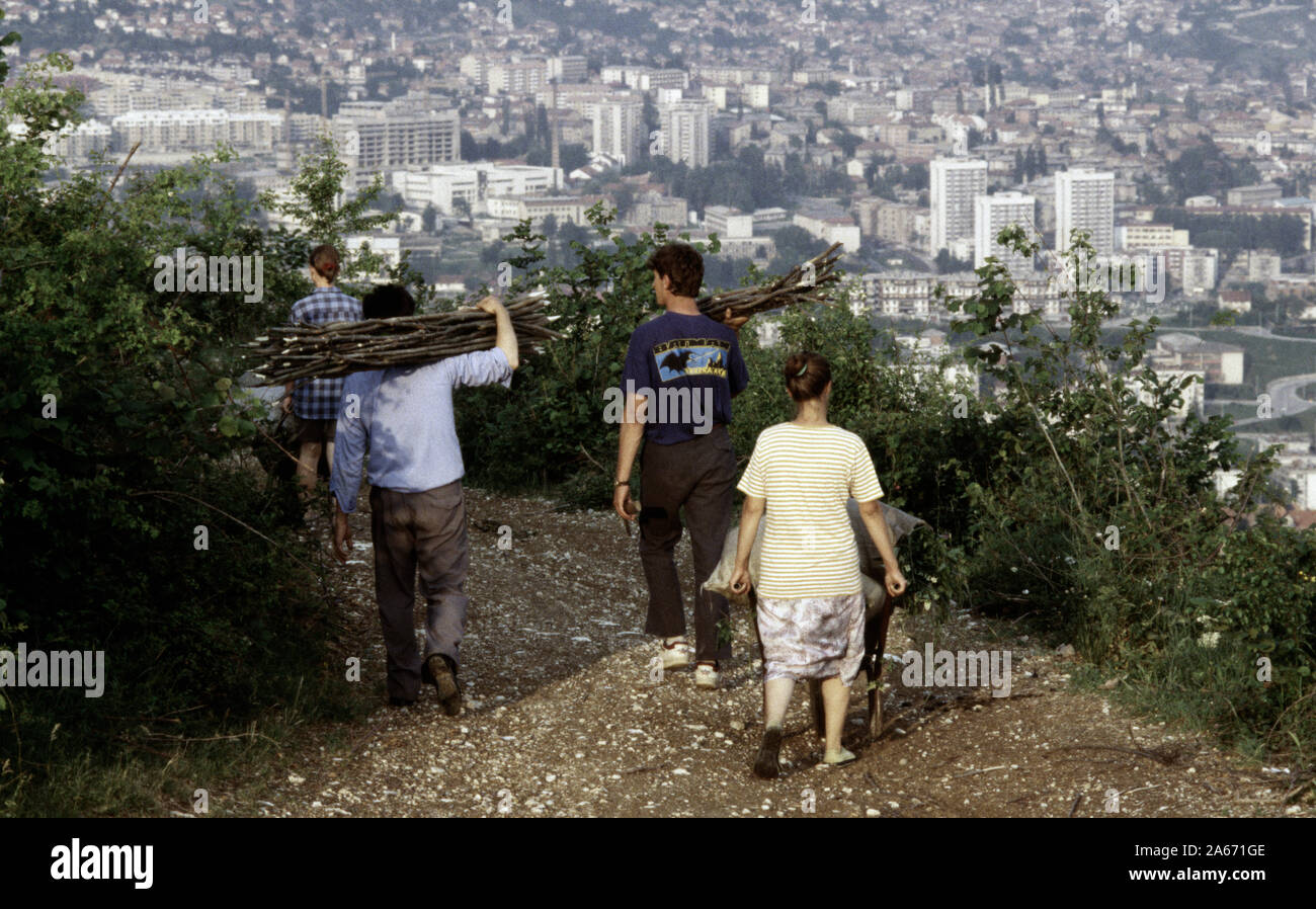 6. Juni 1993 während der Belagerung von Sarajevo: Männer und Frauen tragen frisch Brennholz entlang einer Spur in der Nähe der Oberseite der Hum Hill schneiden. Sarajevo ist ausgestreckt unter ihnen, im Osten, mit der Universität Sarajewo im klinischen Zentrum, wie die Koševo Krankenhaus bekannt, direkt über sie hinaus. Stockfoto