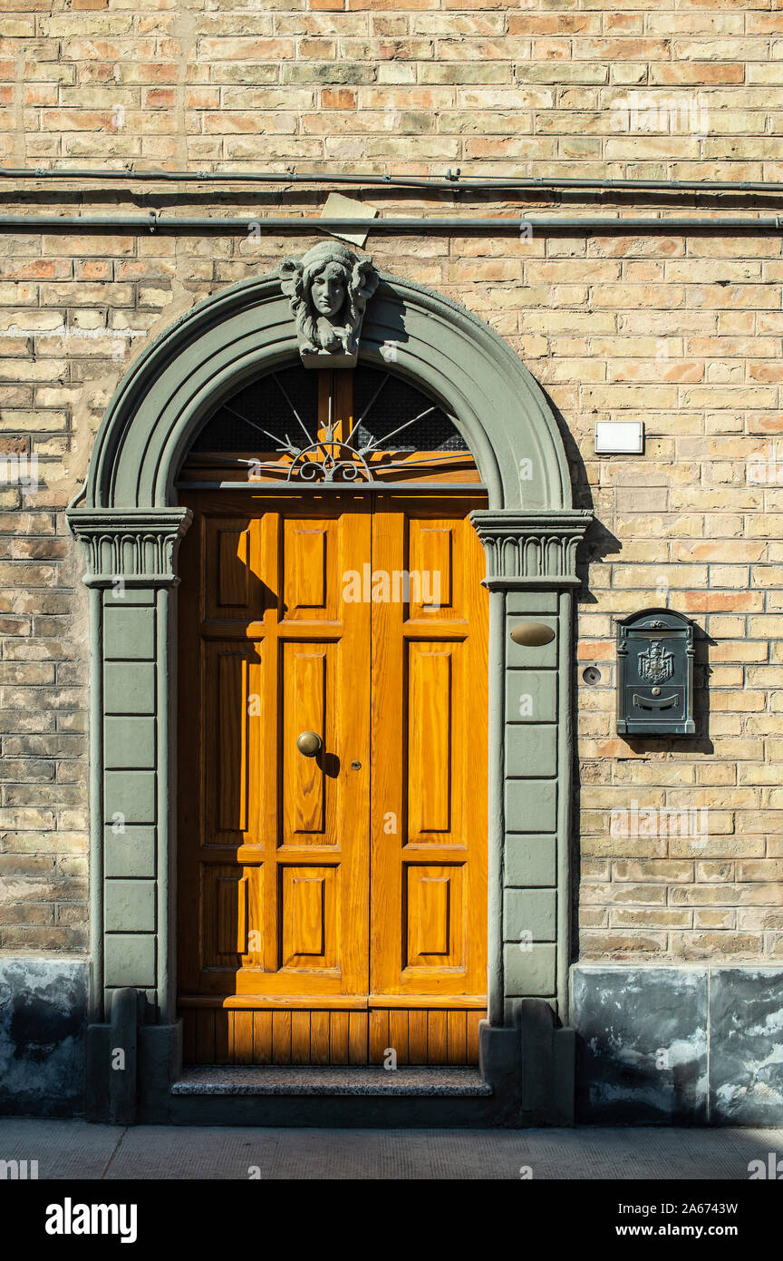 Alte typisch italienischen Holztür. Italienische Haus. Altes haus Fassade. Sonnenlicht. Runde Tür arch. Steinen bauen Haus. Schmiedeeisen Türgriffe. Stockfoto