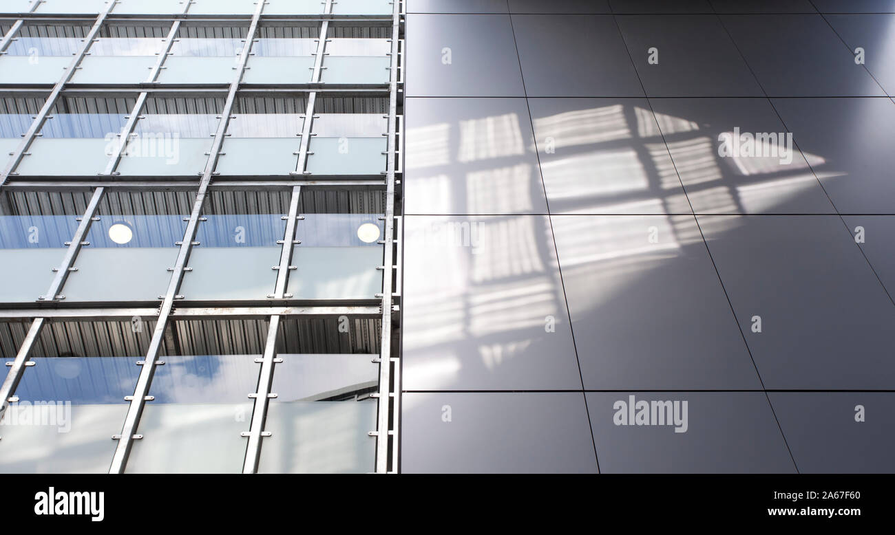 Nahaufnahme der Sonne reflektieren auf modernes Bürogebäude mit hellgrauen Panels und Glas Gehwege Stockfoto