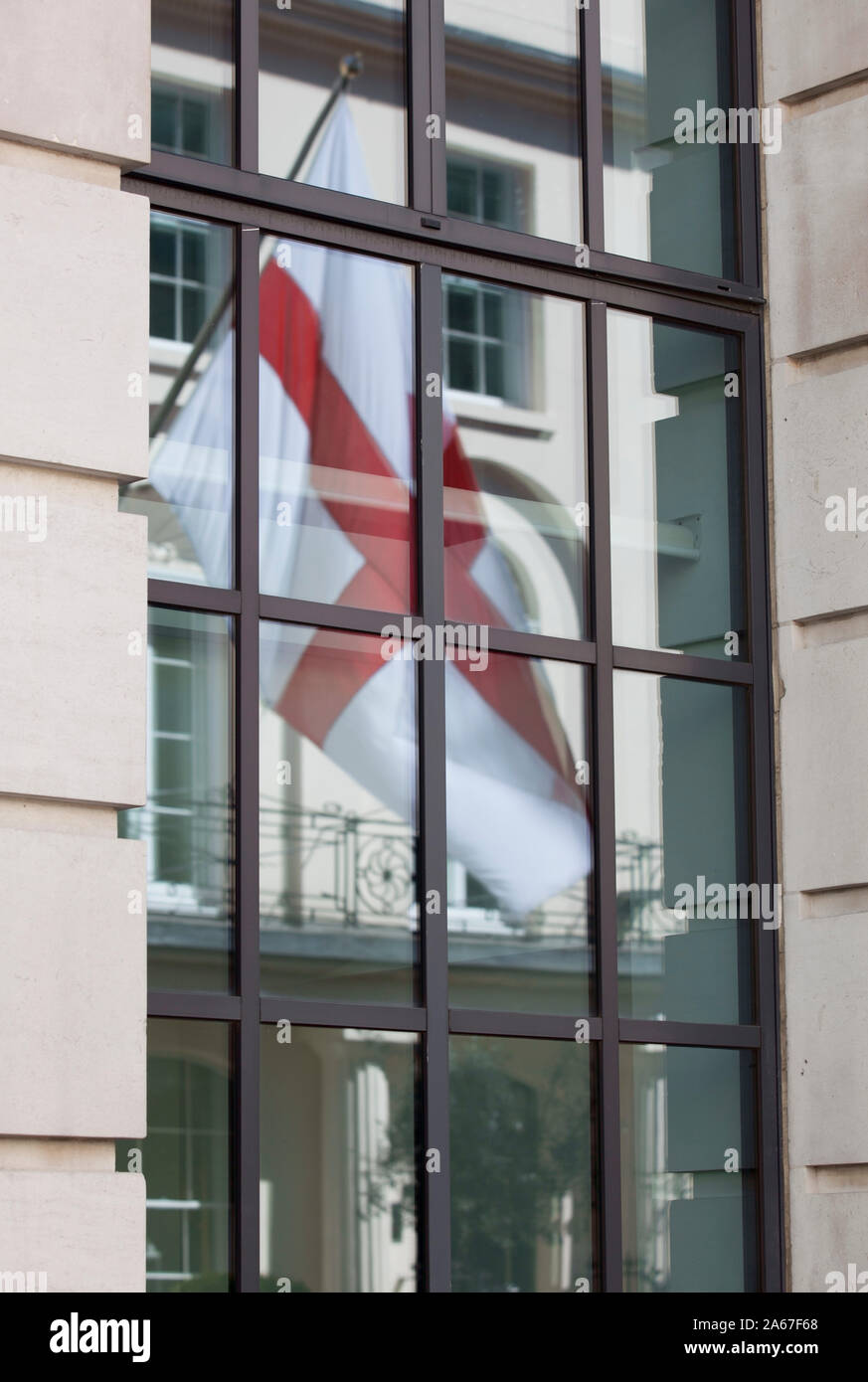 Reflexion der St George Cross Flag im Fenster der Londoner Gebäude Stockfoto