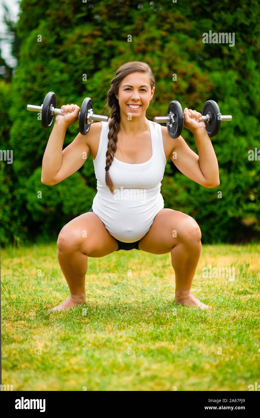 Schwangere Frau Tut Squat Presse Mit Gewichten Im Park Stockfoto