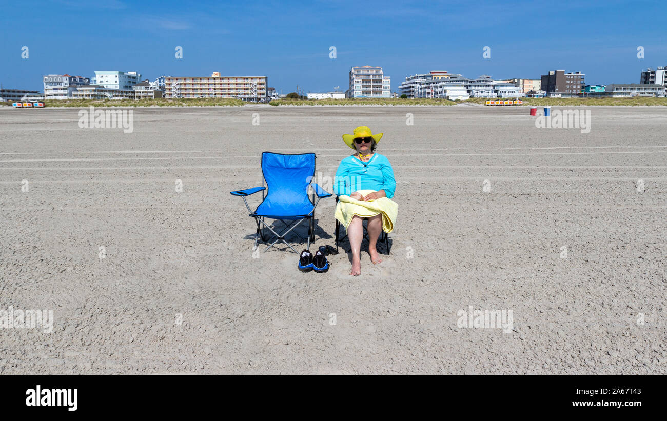 Eine ältere Frau genießen sitzen im Strandkorb in den Sand am Strand durch das Meer. Stockfoto