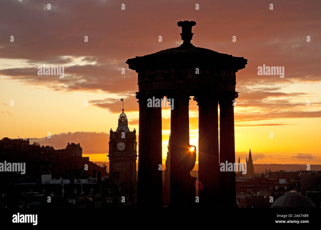 Calton Hill, Edinburgh, Schottland, Großbritannien. 24. Oktober 2019. Farbenfroher Sonnenuntergang über der Innenstadt eine Silhouette von Dugald Stewart Monument und schloss mit Balmoral Hotel im Zentrum. Stockfoto