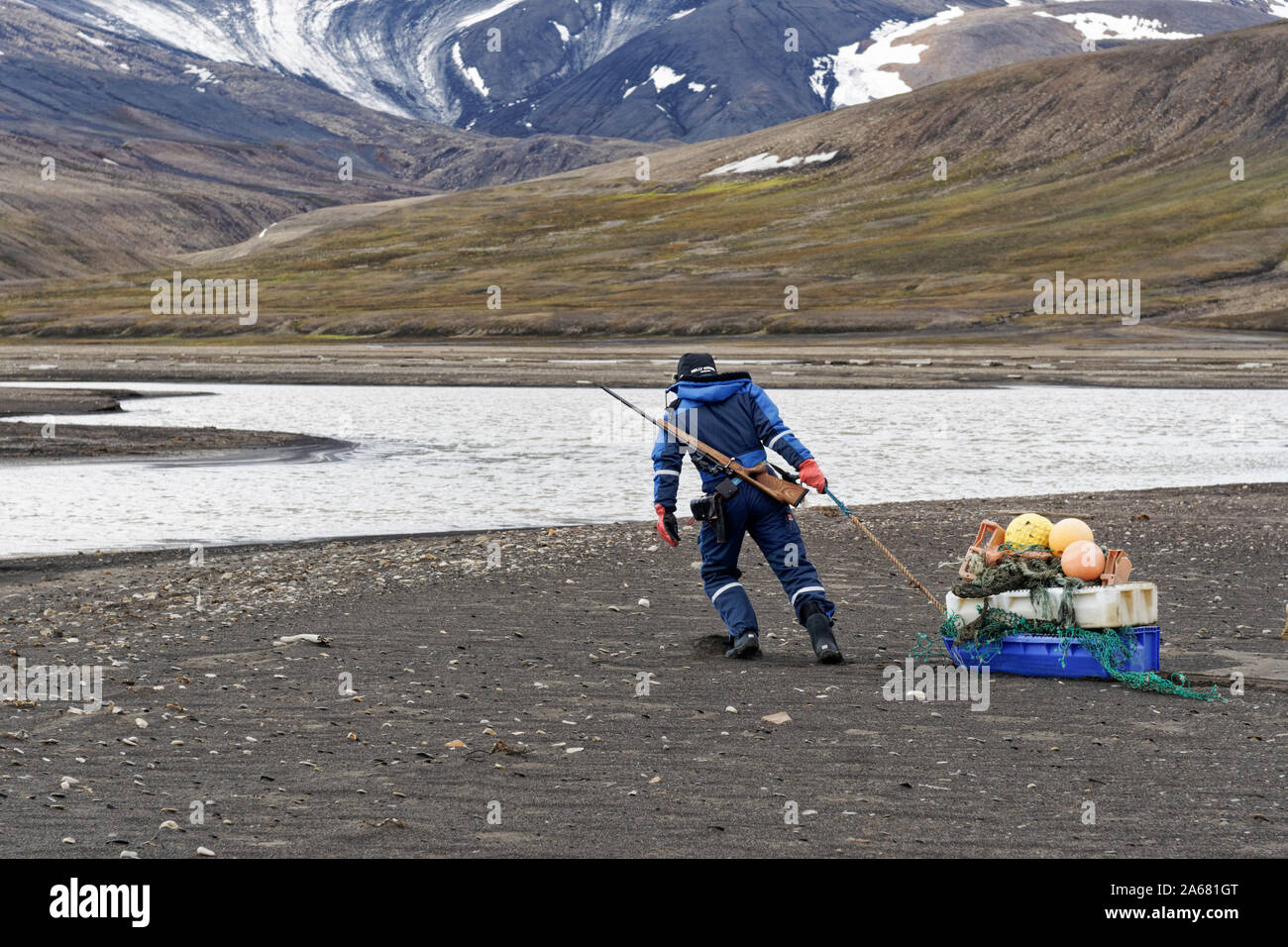 Kunststoffe in der Nähe des Nordpols:Aufräumen der Spitzbergen-Kampagne von Sysselmannen. Ein Freiwilliger zieht Müll zu einer Sammelstelle, Agardhbukta, Svalbard, Norwegen Stockfoto