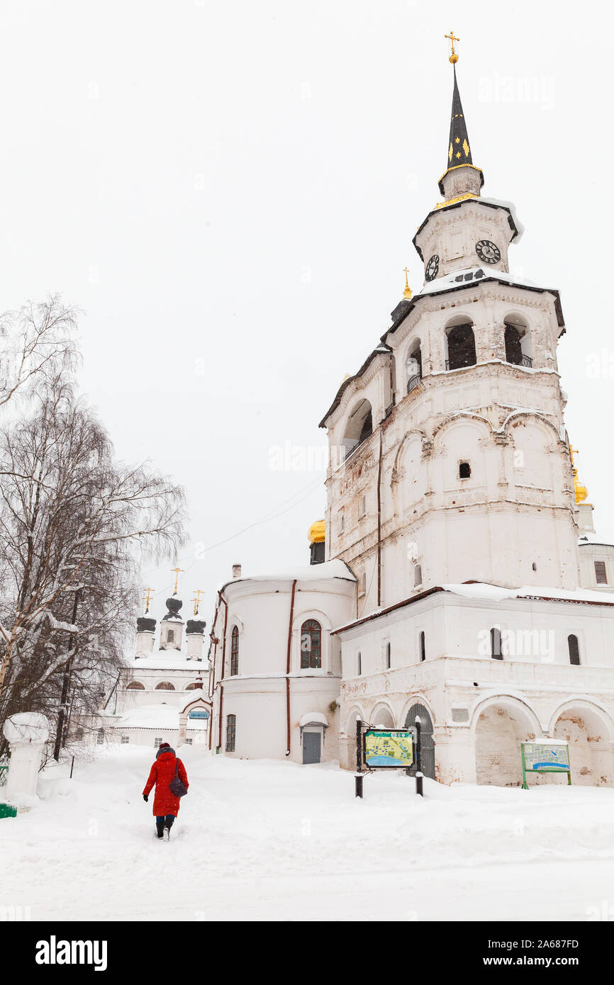 Weliki Ustjug, Russland - Februar 5, 2019: Frau in Rot Spaziergänge in der Nähe der Kathedrale, eine Orthodoxe Kirche in Weliki Ustjug, das älteste Gebäude in Th Stockfoto