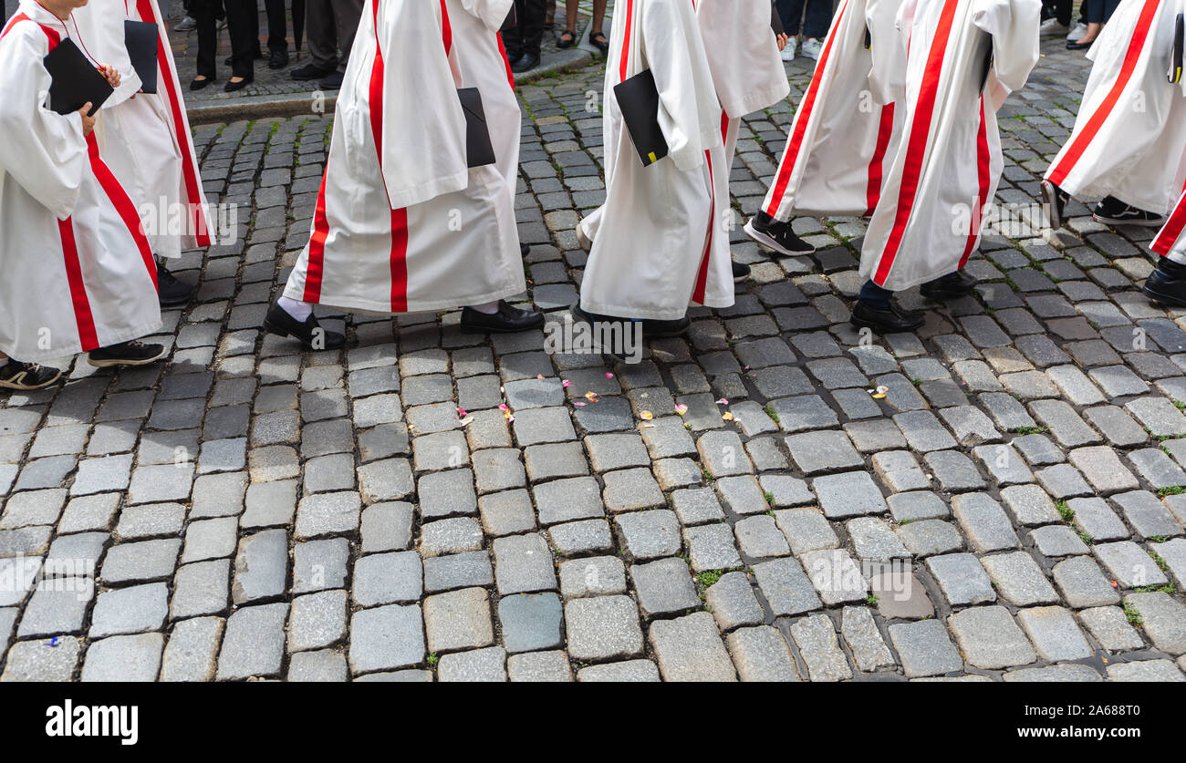 Ministranten in Uniform zu Fuß auf einer gepflasterten Straße Stockfoto