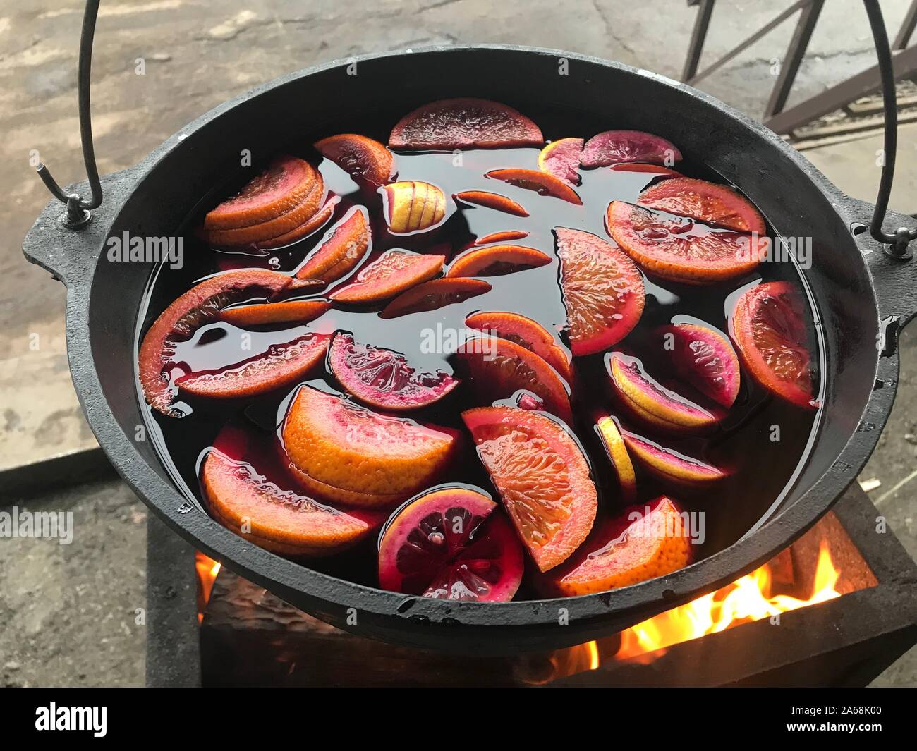 Glühwein mit Früchten in den großen Kessel auf Feuer closeup gekocht Stockfoto