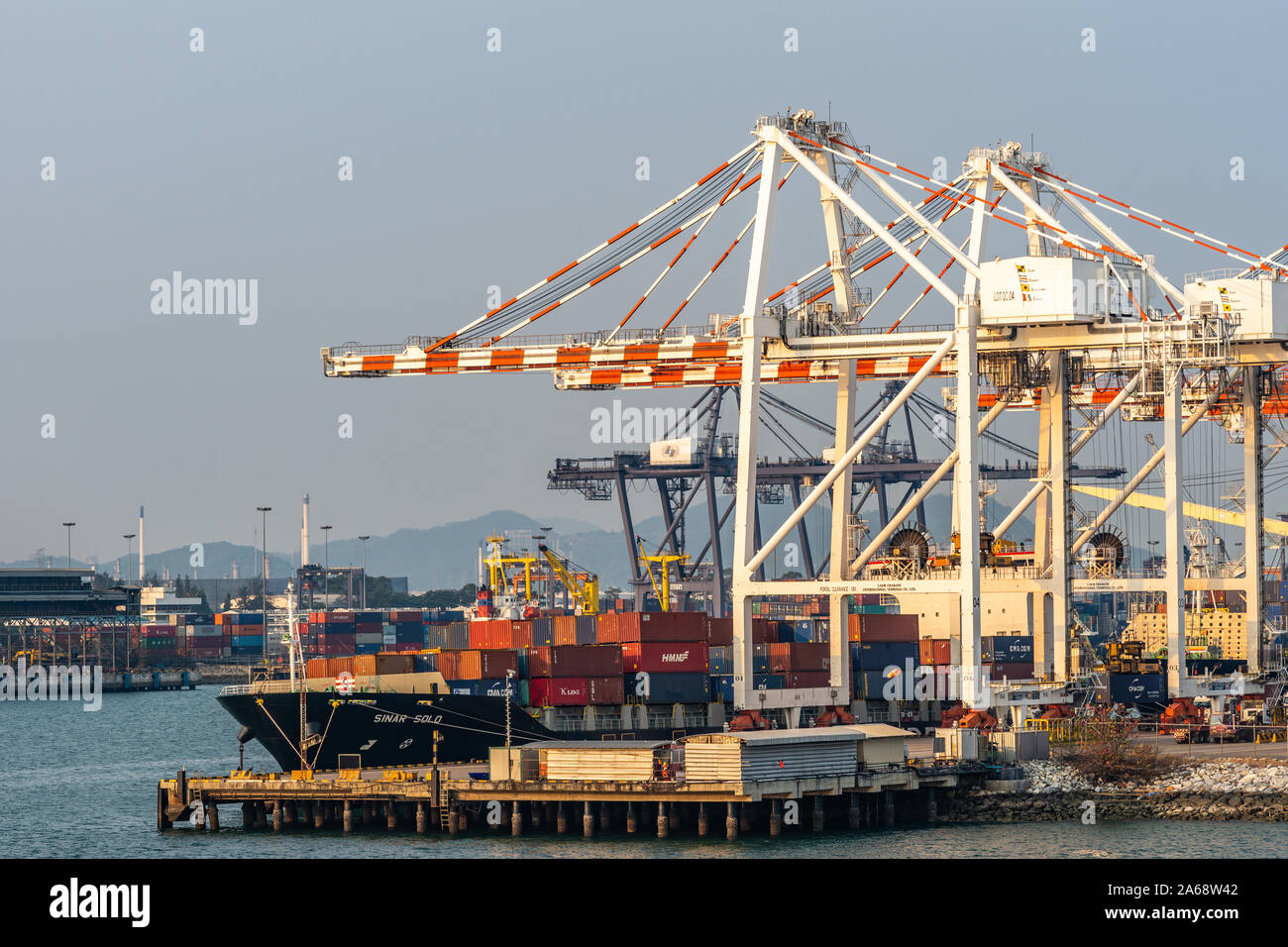 Laem Chabang Seehafen, Thailand - 17. März 2019: Große rote und weiße Containerbrücken arbeit Sinar Solo Containerschiff, Singapur gekennzeichnet, unter Sonnenuntergang s Stockfoto