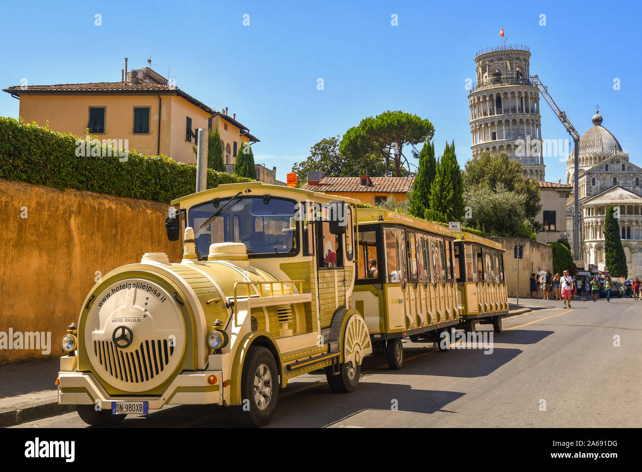 Ein touristischer Zug im historischen Zentrum von Pisa geparkt, mit dem berühmten Schiefen Turm auf der Piazza dei Miracoli im Hintergrund, Toskana, Italien Stockfoto