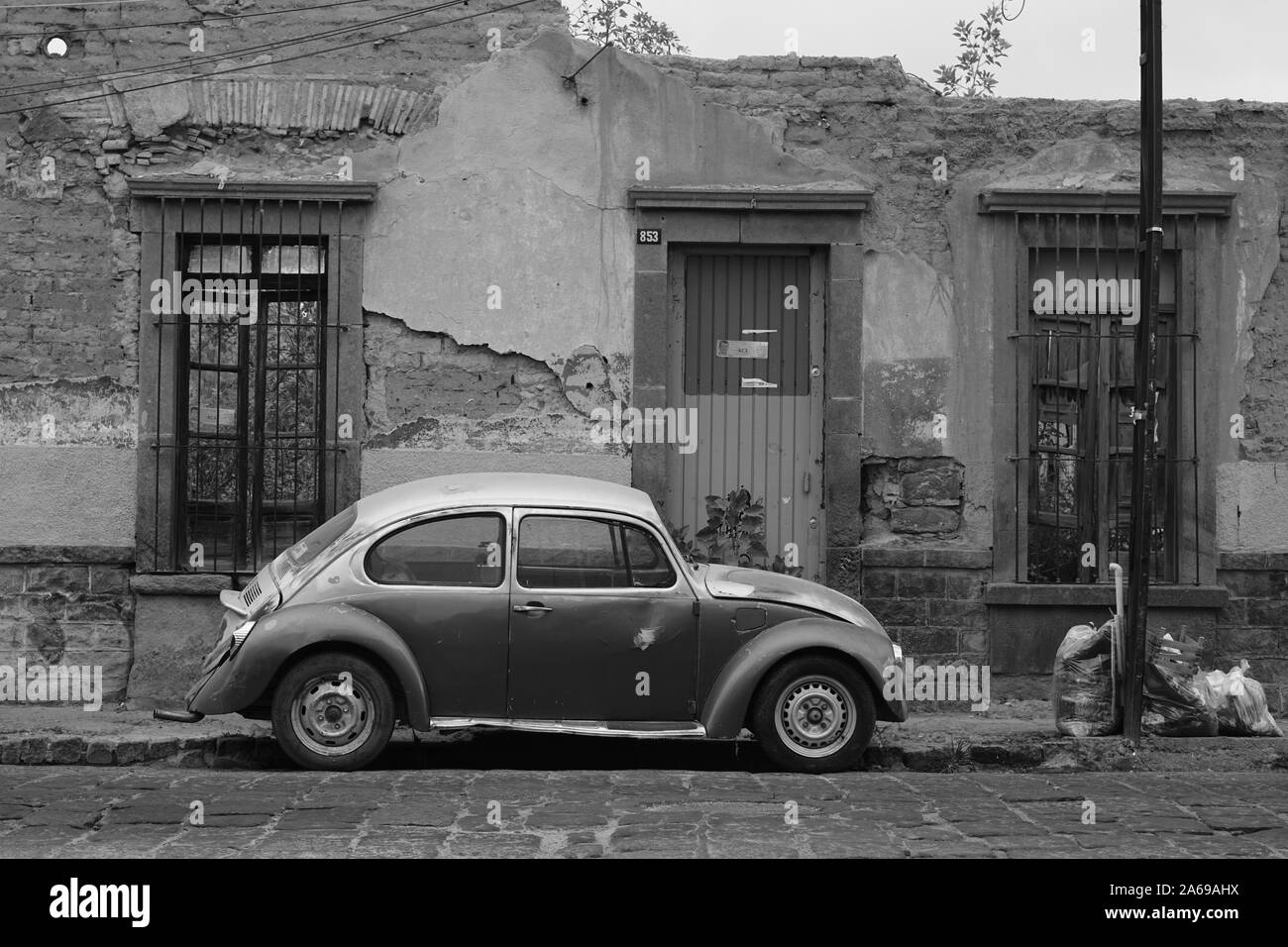 Oldtimer Volkswagen Bug parkte auf der Straße in San Luis Potosi, Mexiko. Beetle vor dem alten historischen Haus geparkt. Stockfoto