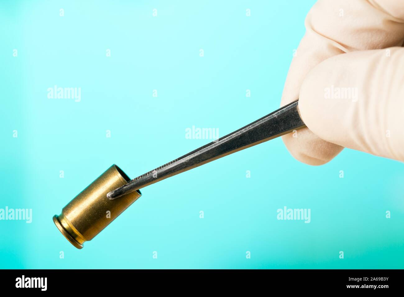 Crime Scene Investigation CSI forensische Beweise sammeln bullet Gehäuse mit Pinzette - Polizei, Beweise oder forensischen Untersuchung Konzept, auf Blau b Stockfoto