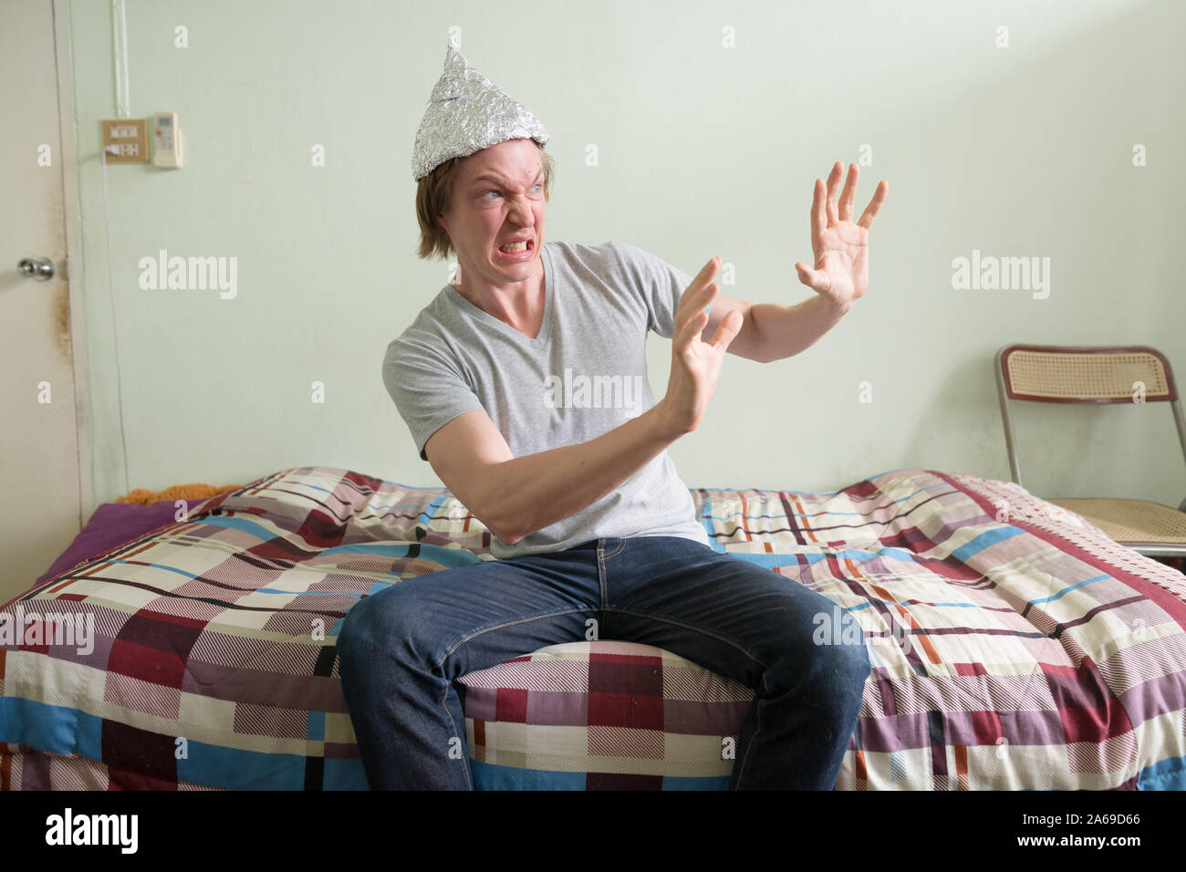 Junger Mann mit Alufolie hat Gefühl im Schlafzimmer Angst Angst Stockfoto