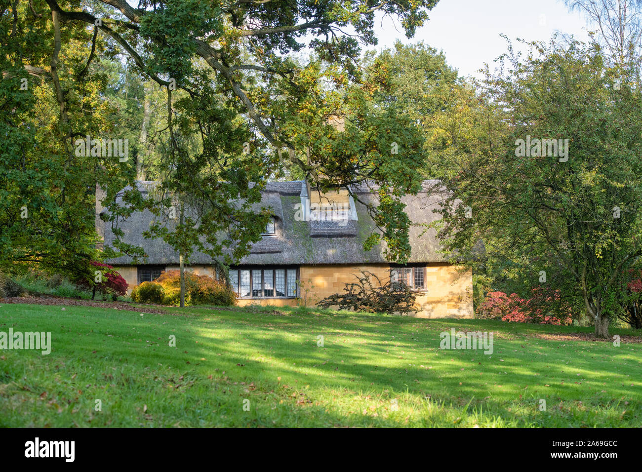 Reetdachhaus und Bäume im Herbst bei Batsford Arboretum, Cotswolds, Moreton-in-Marsh, Gloucestershire, England Stockfoto