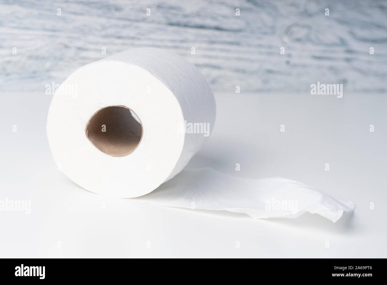 Klopapierrolle auf einem weißen Tisch vor dem Hintergrund einer Holz- strukturelle blaue Wand als Gruppe planen. Das Konzept der Sanftheit und Zärtlichkeit Stockfoto