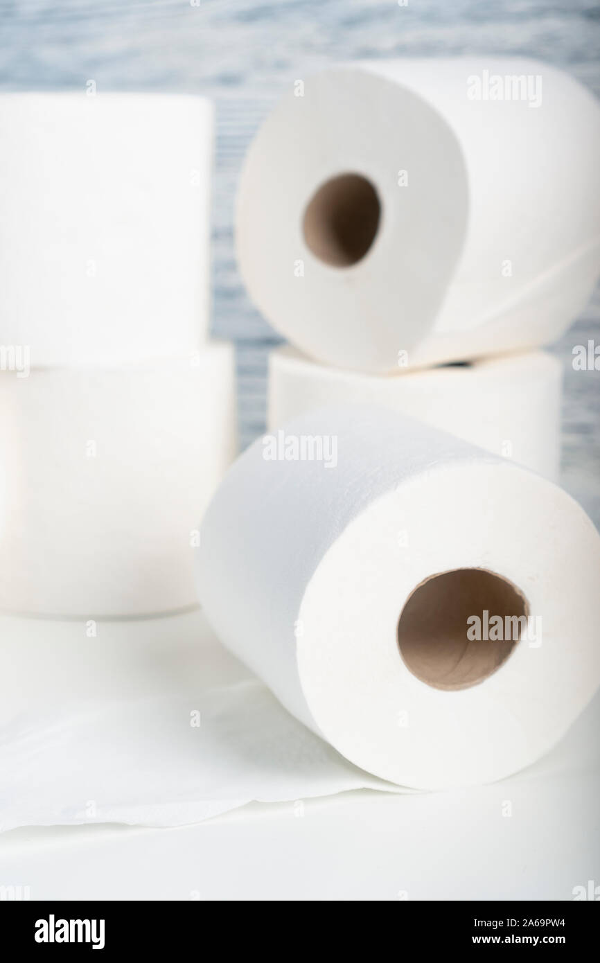 Ein Haufen von Toilettenpapierrollen auf einem weißen Tisch auf dem Hintergrund der blauen Wand Textur. Das Konzept der Verwendung von natürlichen Materialien für Hygieneprodukte Stockfoto