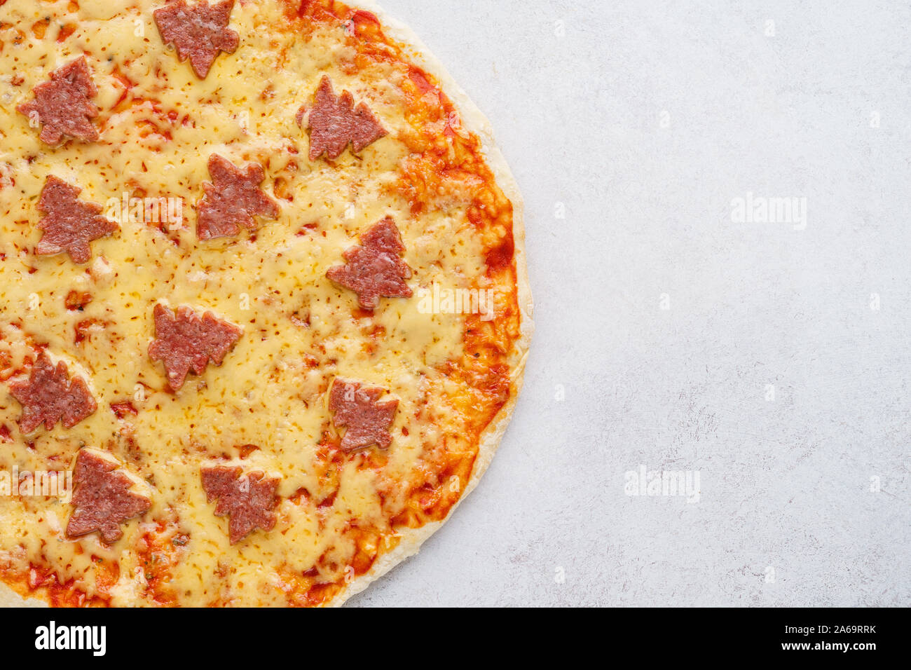 Die Hälfte eines Weihnachten Pepperoni Pizza mit Tannen eingerichtet. Ansicht von oben. Kopieren Sie Platz. Stockfoto