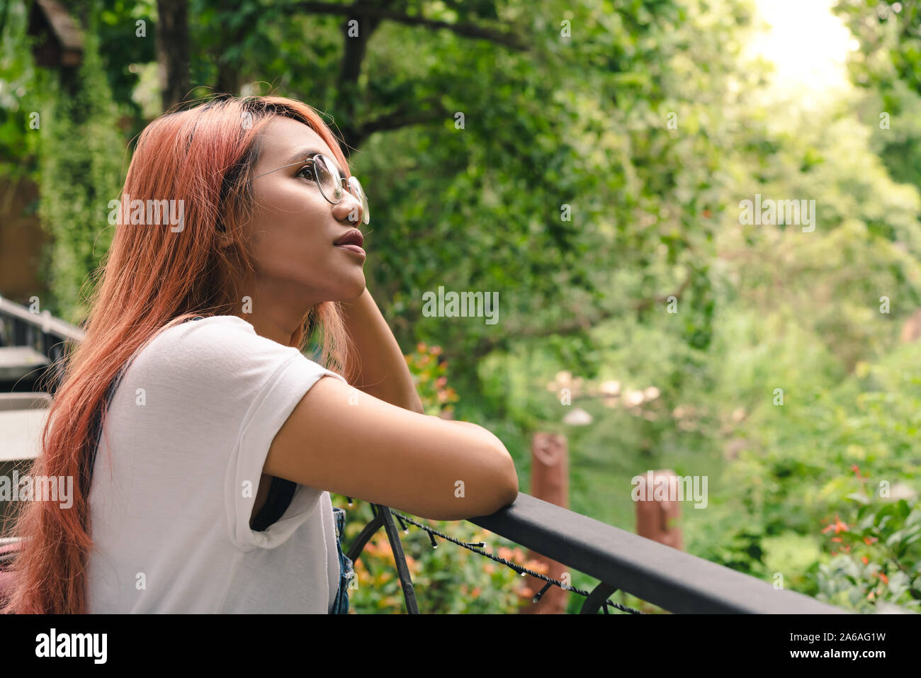 Trendige junge ethnische Mädchen mit roten Haaren steht auf Garten Balkon mit Blick auf den asiatischen Lifestyle Frau genießen, Leben auf dem Land Urlaub im schönen Villa Resort - Erholung, Ruhe und Freizeit Konzept Stockfoto