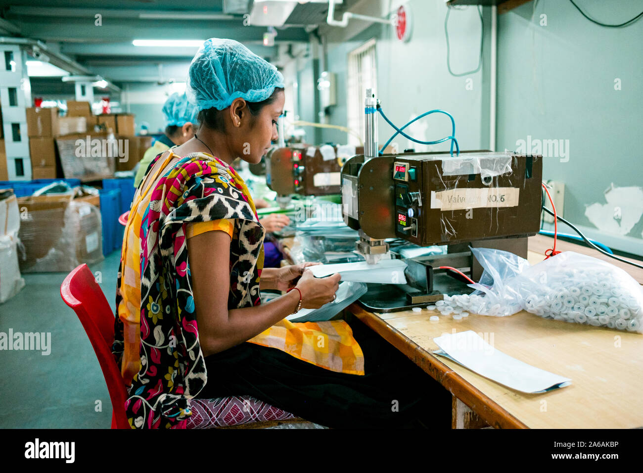 New Delhi, Indien - 10. September 2019: eine indische Frau an mit industriellen Anlagen arbeiten im Inneren der Verpackung Produktionsstätte mit heiteren Ausdruck Stockfoto