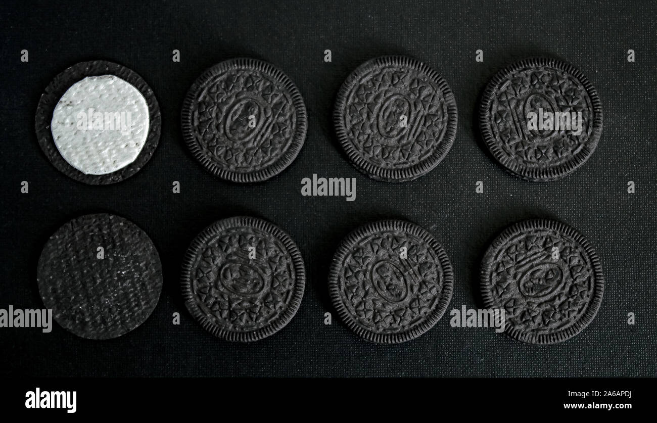 Schwarz Cookies in zwei Reihen mit einem weißen Creme Zentrum auf einer schwarzen Leinwand Hintergrund in dunklen Farben. Stockfoto