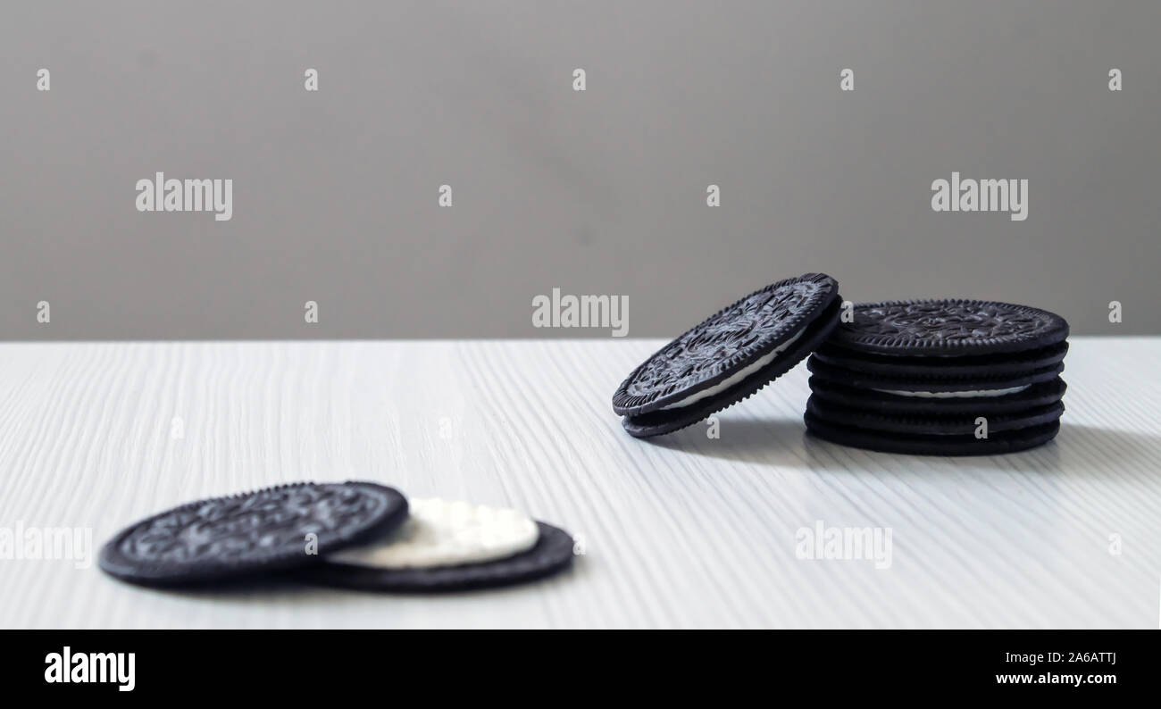 Schwarz cookies ständigen Pinnacle mit weißer Creme Center auf einem weißen Holz- Hintergrund. Stockfoto