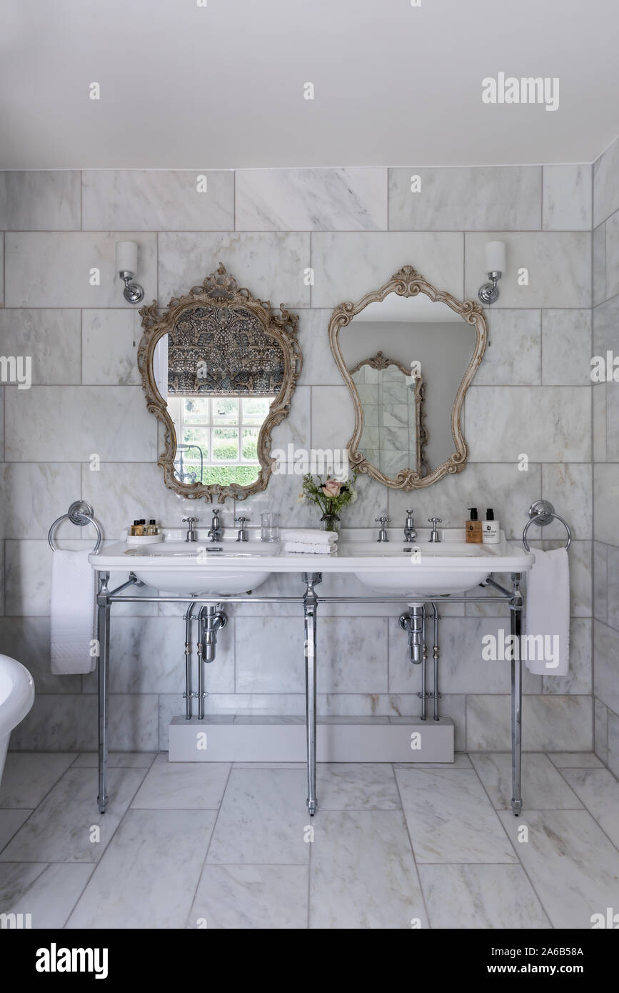 1930er Jahre Art Deco Stil dekorative Spiegel über Doppelwaschbecken im Badezimmer aus Marmor. Stockfoto