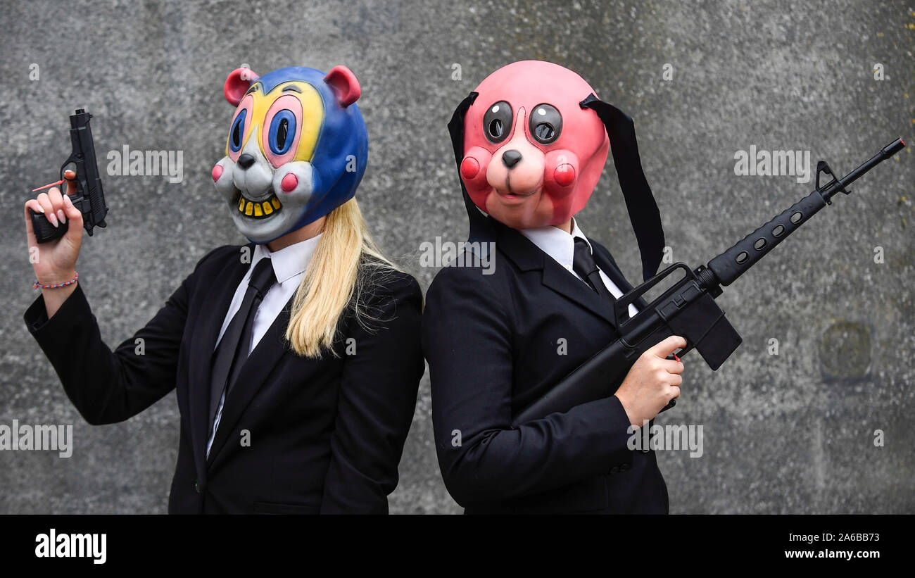 London, Großbritannien. 25. Oktober 2019. Frauen gekleidet als (L und R)  Cha Cha und Hazel von der Umbrella Academy TV zeigen andere cosplayer aus  der ganzen Welt an der Eröffnung Tag der