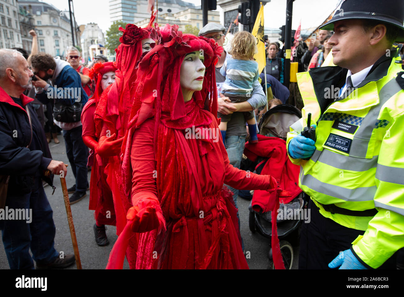 London, 10. Oktober 2019, vom Aussterben Rebellion Gruppe in rot Kostüme surround Polizei acivists vorbereiten, die sich um eine Holz- struktur in der Straße neben dem Trafalgar Square gesperrt haben zu verhaften. Stockfoto