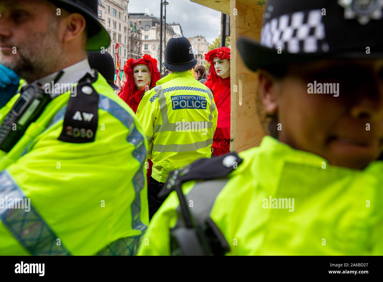 London, 10. Oktober 2019, vom Aussterben Rebellion Gruppe in rot Kostüme surround Polizei acivists vorbereiten, die sich um eine Holz- struktur in der Straße neben dem Trafalgar Square gesperrt haben zu verhaften. Stockfoto
