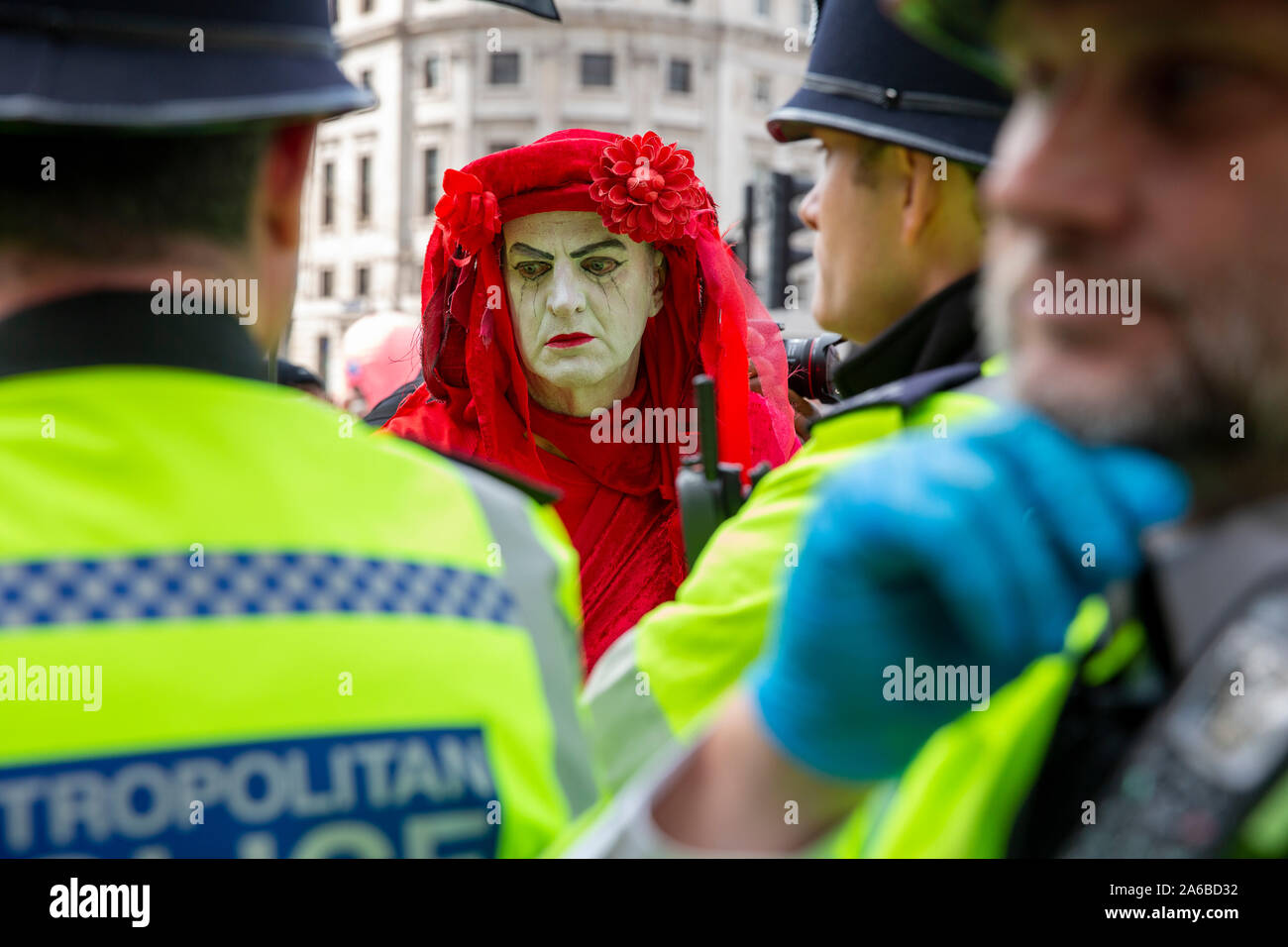 London, 10. Oktober 2019, vom Aussterben Rebellion Gruppe in rot Kostüme surround Polizei acivists vorbereiten, die sich um eine Holz- struktur in der Straße neben dem Trafalgar Square gesperrt haben zu verhaften. Stockfoto