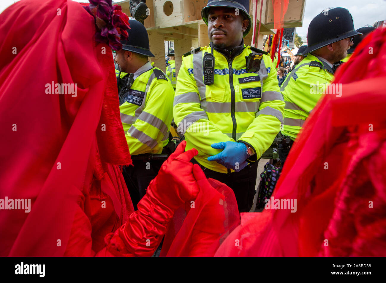 London, 10. Oktober 2019, vom Aussterben Rebellion Gruppe in rot Kostüme surround Polizei acivists vorbereiten, die sich um eine Holz- struktur in der Straße neben dem Trafalgar Square gesperrt haben zu verhaften. Stockfoto