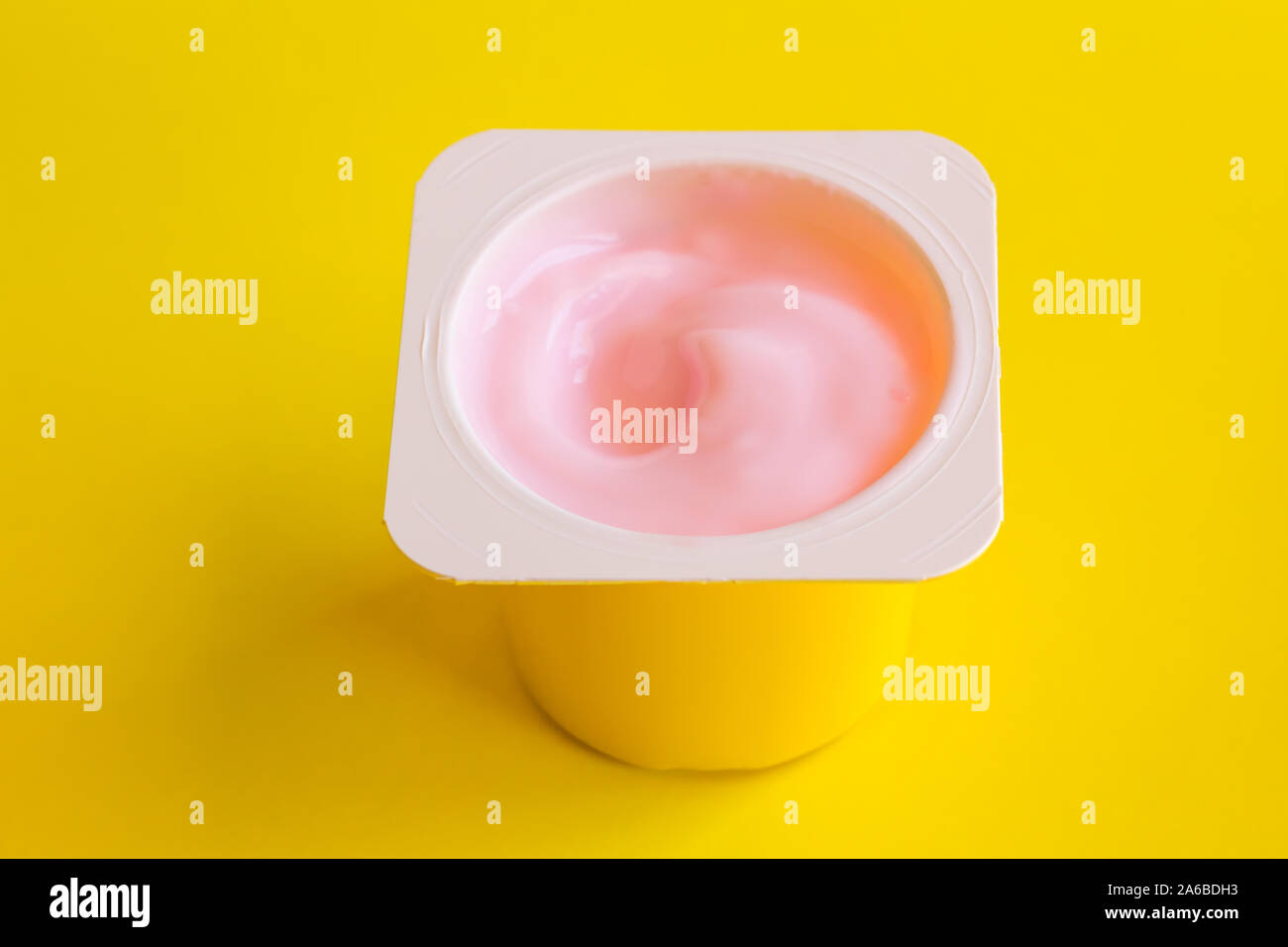 Strawberrry rosa Joghurt in gelb Plastikbecher auf gelben Hintergrund mit Leerzeichen getrennt für Text Stockfoto