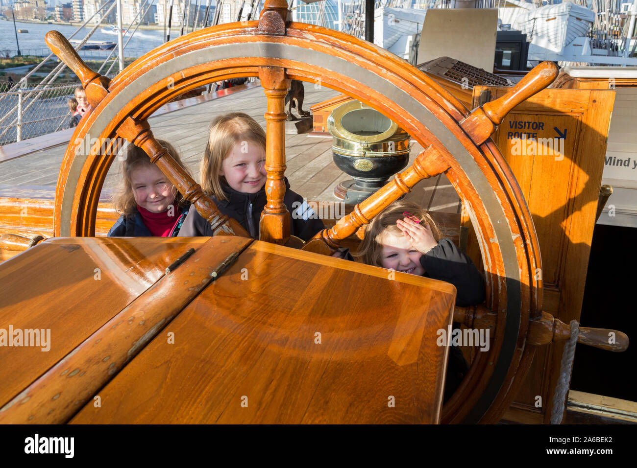 Touristische Besucher Kinder Jungen Mädchen, Schwestern, durch die (Lenkung) Rad suchen auf dem Hauptdeck von der Segelschiff Cutty Sark. Greenwich, London. UK. (105) Stockfoto