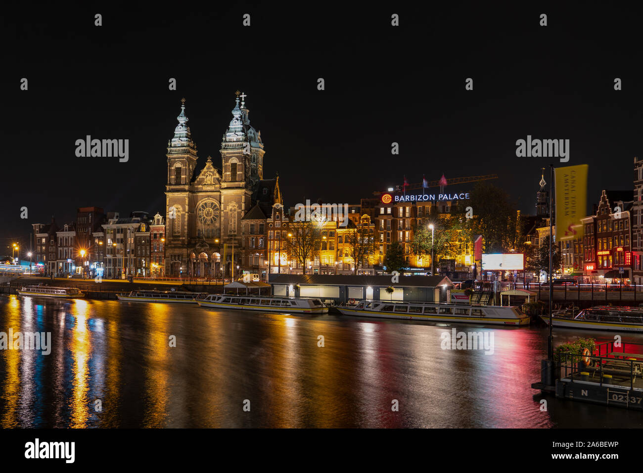 Amsterdam/Holland - Oktober 06, 2019: Night city Blick auf Amsterdam Canal, Basilika des Heiligen Nikolaus und Barbizon Palace, Niederlande. Lange Belichtung. Stockfoto