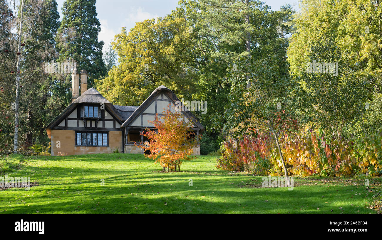 Reetdachhaus und Bäume im Herbst bei Batsford Arboretum, Cotswolds, Moreton-in-Marsh, Gloucestershire, England. Stockfoto