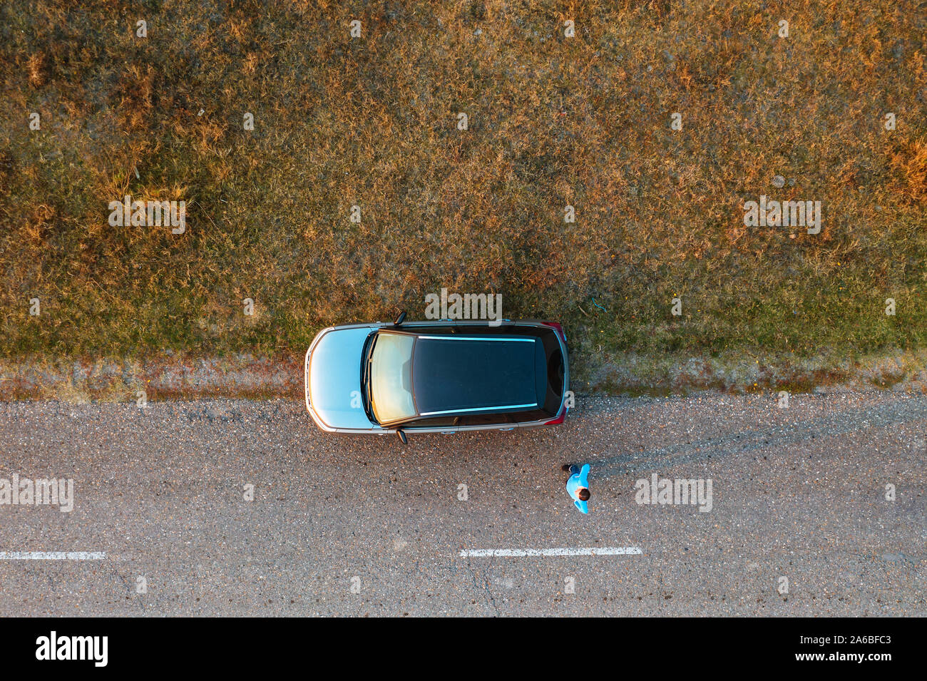 Frau und Auto auf der Straße durch grasartige Wastelands, Luftaufnahme direkt oberhalb von Drone pov Stockfoto