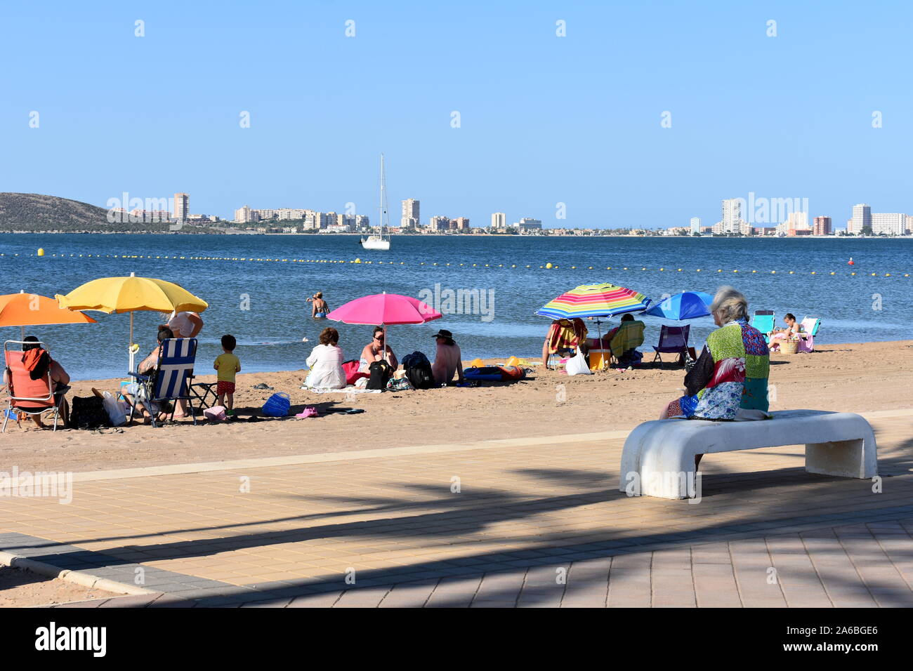Urlauber am Strand von Mar de Cristal, Mar Menor, Murcia, Spanien sitzen Stockfoto