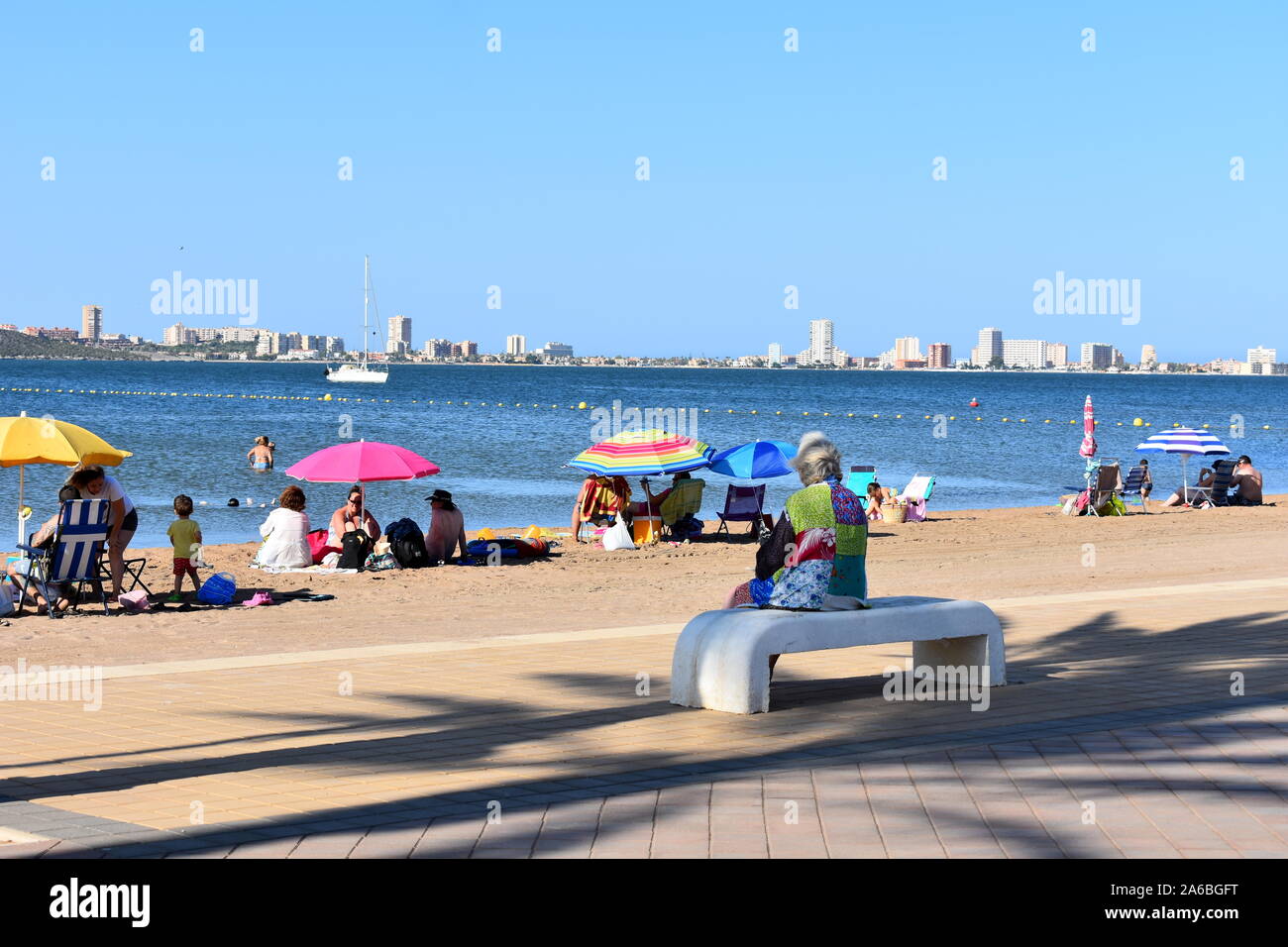 Urlauber am Strand von Mar de Cristal, Mar Menor, Murcia, Spanien sitzen Stockfoto
