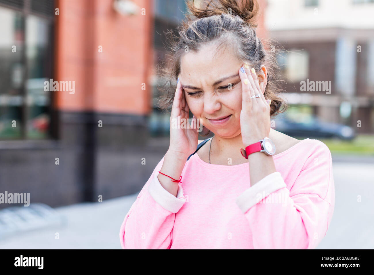 Junge kaukasier Frau winces halten ihren Kopf Kopfschmerzen leiden, im Sommer auf der Straße. Stockfoto