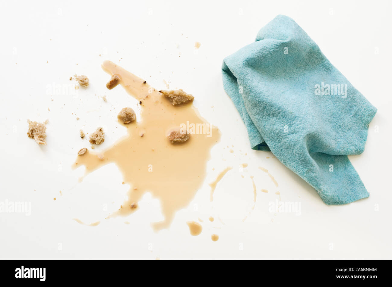 Verschütteter Kaffee, Brot, Krümel und abwaschtücher auf weißer Tisch. Stockfoto
