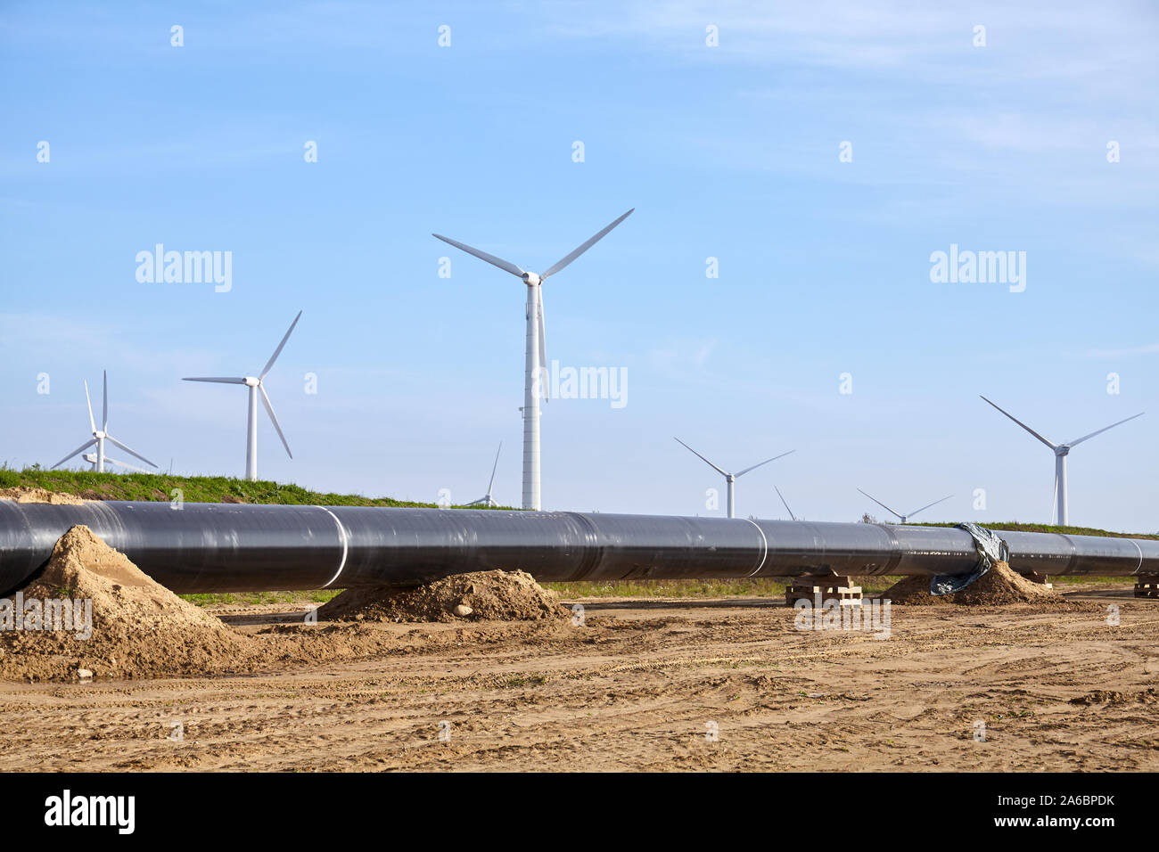 Pipeline Baustelle an einem sonnigen Tag, Windmill Farm im Hintergrund. Stockfoto