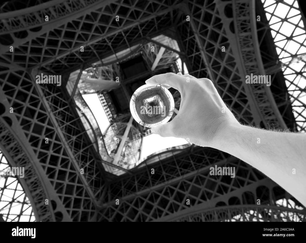 Kugel aus Glas unter dem Eiffelturm auf die Hand des Menschen mit schwarzen und weißen Farbtönen Wirkung Stockfoto