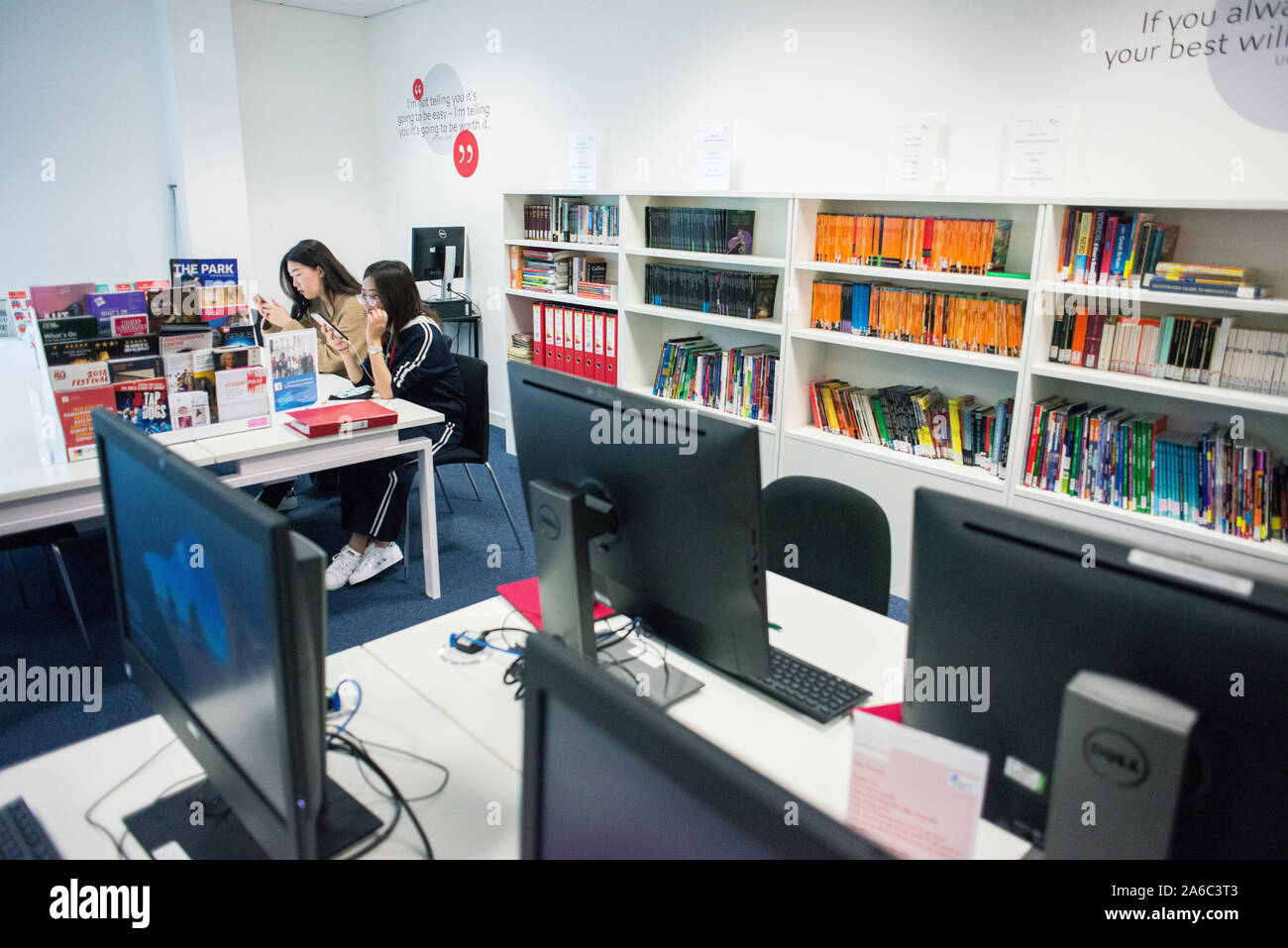Einer Universität oder einem College Bibliothek mit Büchern in den Regalen, Studenten und Computer Stockfoto