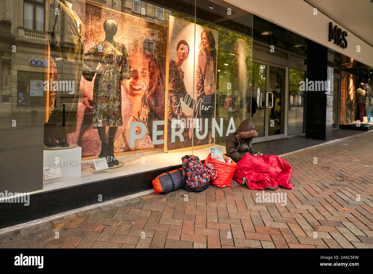Eine obdachlose Frauen Handy außerhalb M&S in Gloucester sitzen Stockfoto