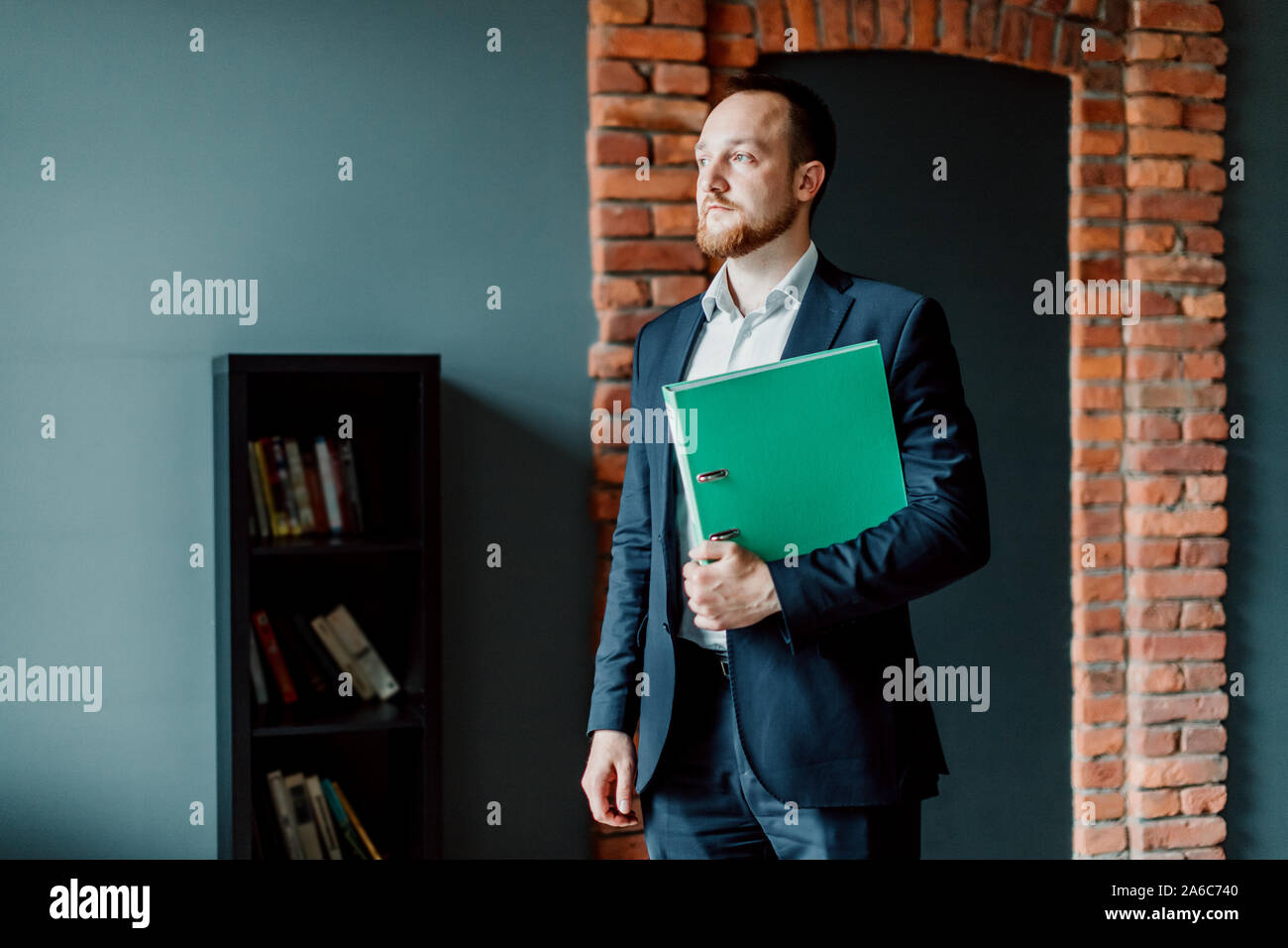 Erfolgreiche Buchhalter in einem Anzug steht und mit einem grünen Ordner in seinen Händen. Stockfoto