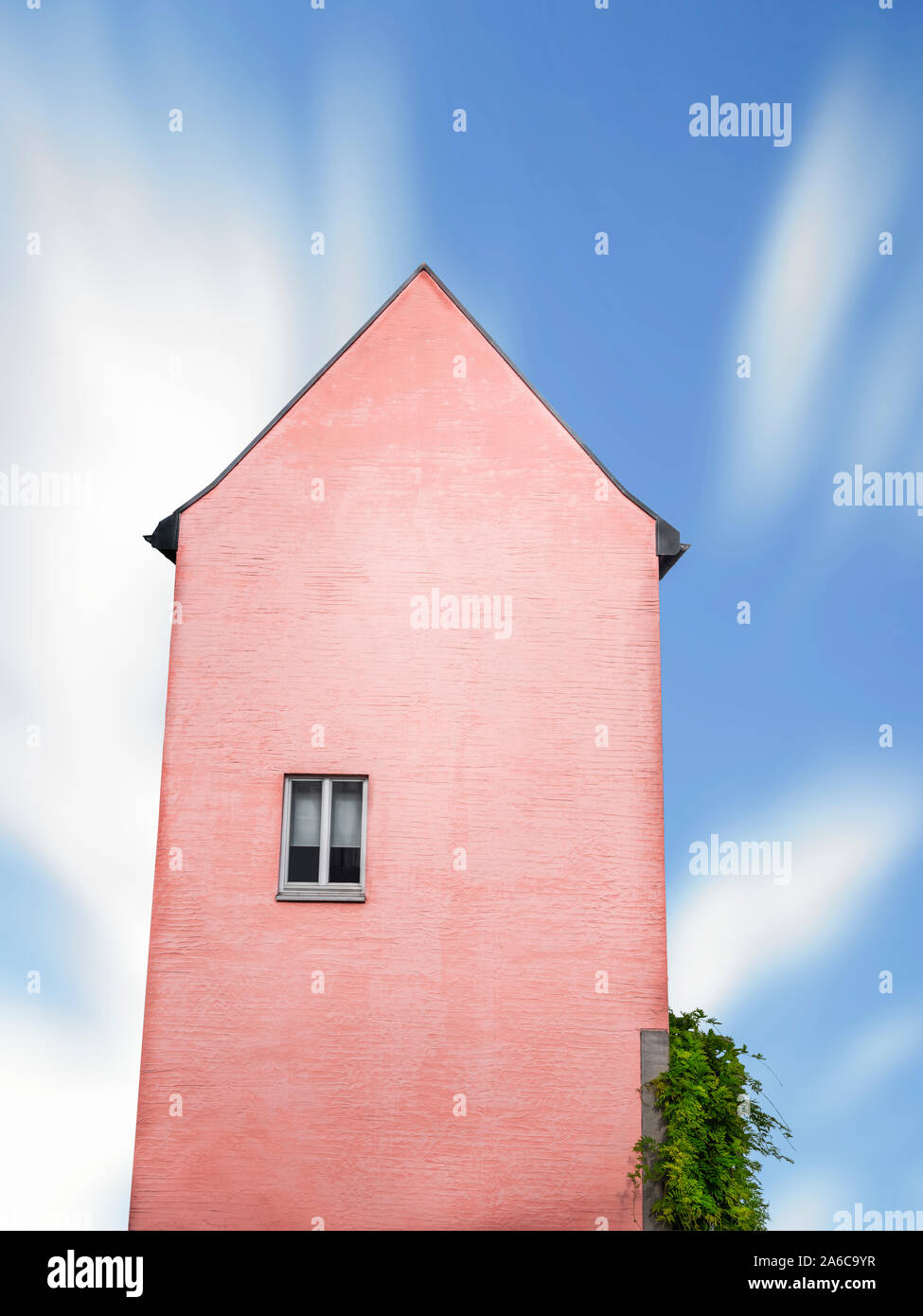 Coral Gebäude Turm mit einem Fenster gegen einen blauen Himmel. Deutsche altes Haus, groß, mit nur einem Fenster, isoliert. Minimale surreale Architektur. Stockfoto