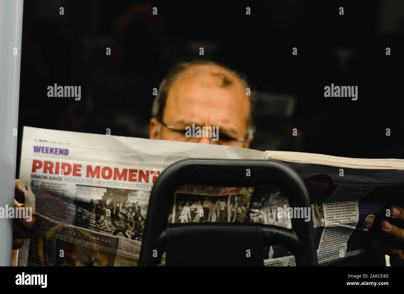 Mittleres Alter Mann sehr fokussiert ist eine Zeitung lesen in der U-Bahn. Schlagzeilen der Artikel ist 'Pride' Stockfoto