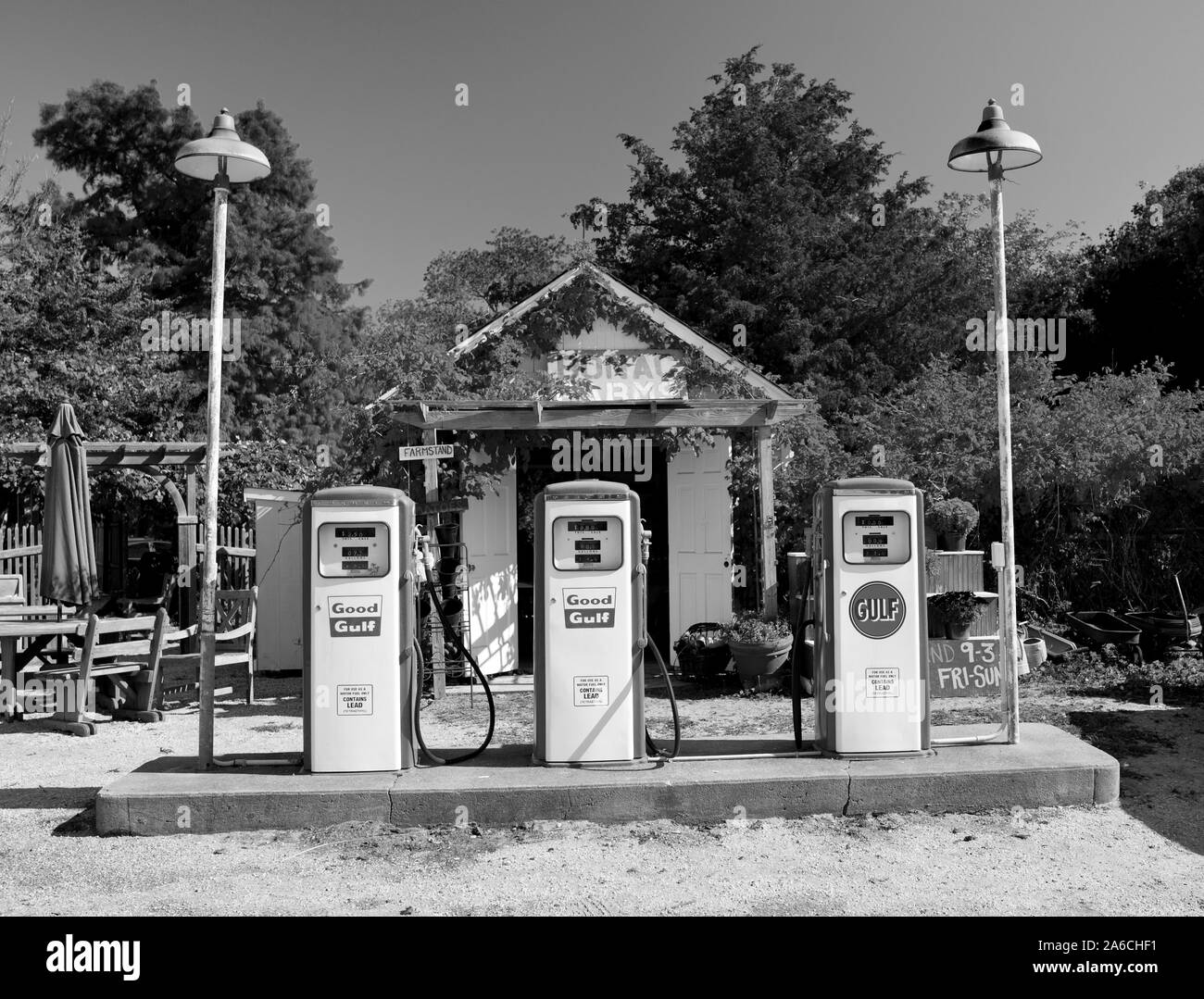 Drei antiken gas Pumpen mit Schmutz der Straße. Kleine in der hinteren Halle. Ländliche Umgebung mit Bäumen und Reben. Farbige horizontale Foto. Stockfoto