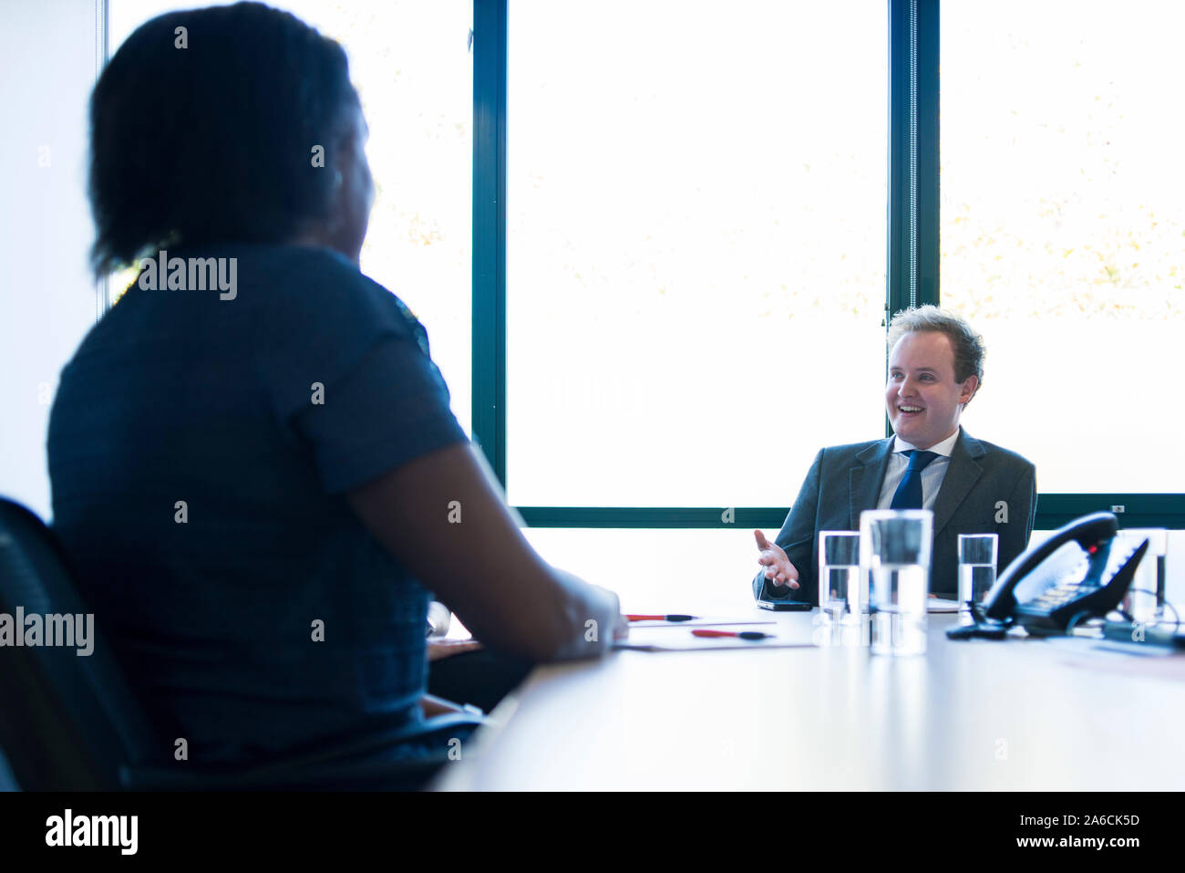 Eine schwarze Frau sitzt an einem Tisch in einer Chancengleichheit Business Stockfoto